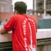 Male model wearing red Mucky Shovel graphic T-shirt, back view.