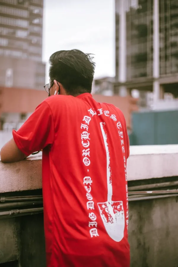 Male model wearing red Mucky Shovel graphic T-shirt, back view.
